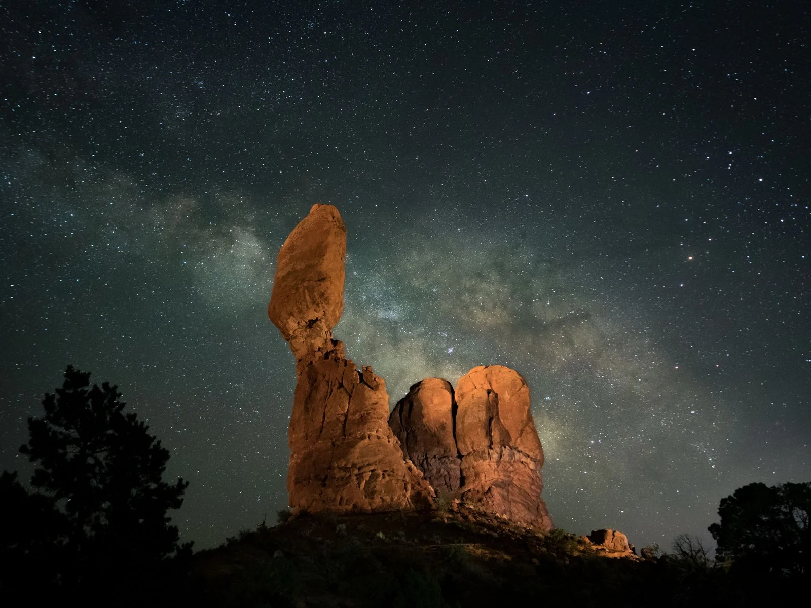 Captivating night sky with Milky Way arching over Balanced Rock in Utah's Arches National Park.