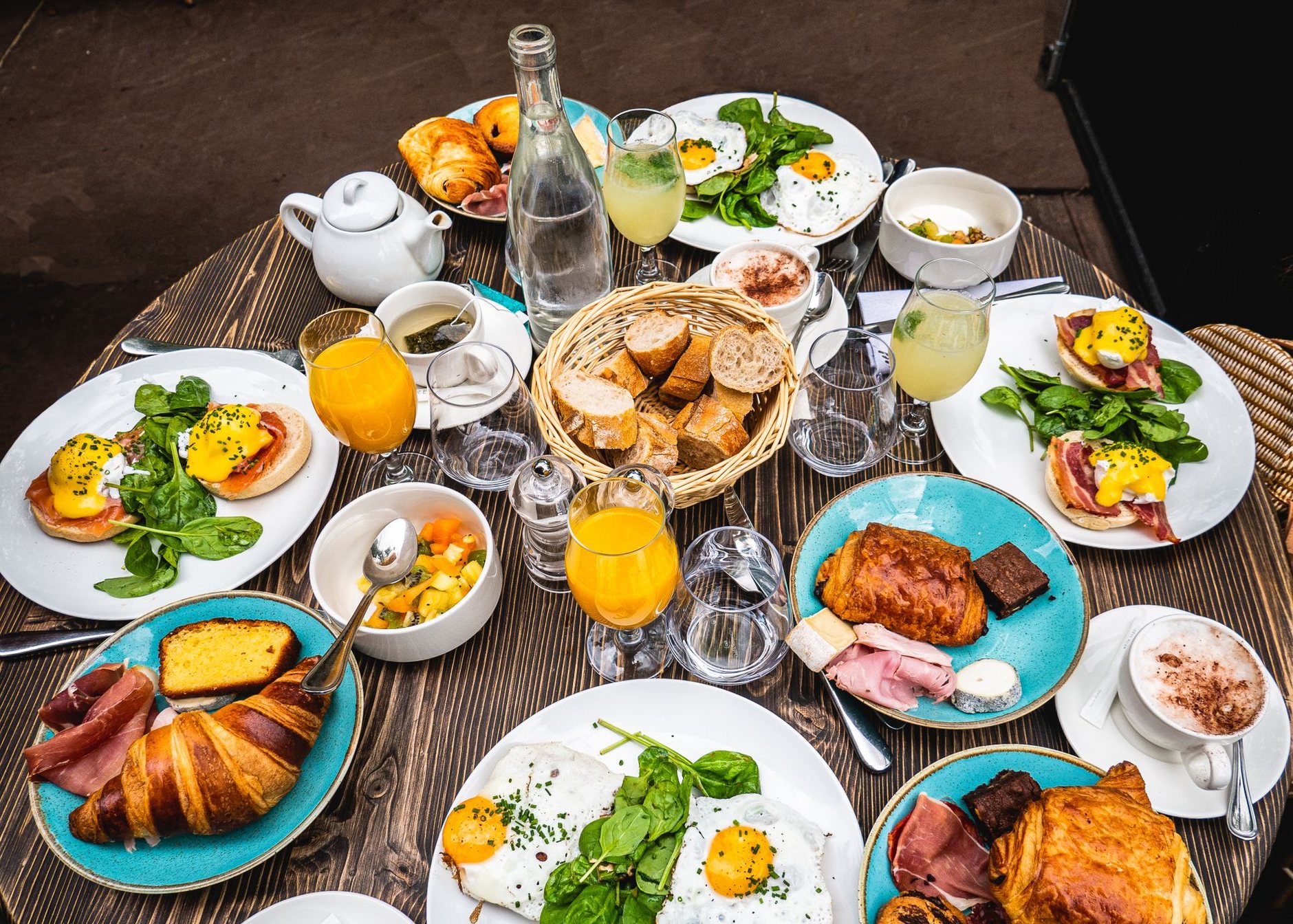 A brunch table spread with eggs Benedict, croissants, fresh juice and coffee
