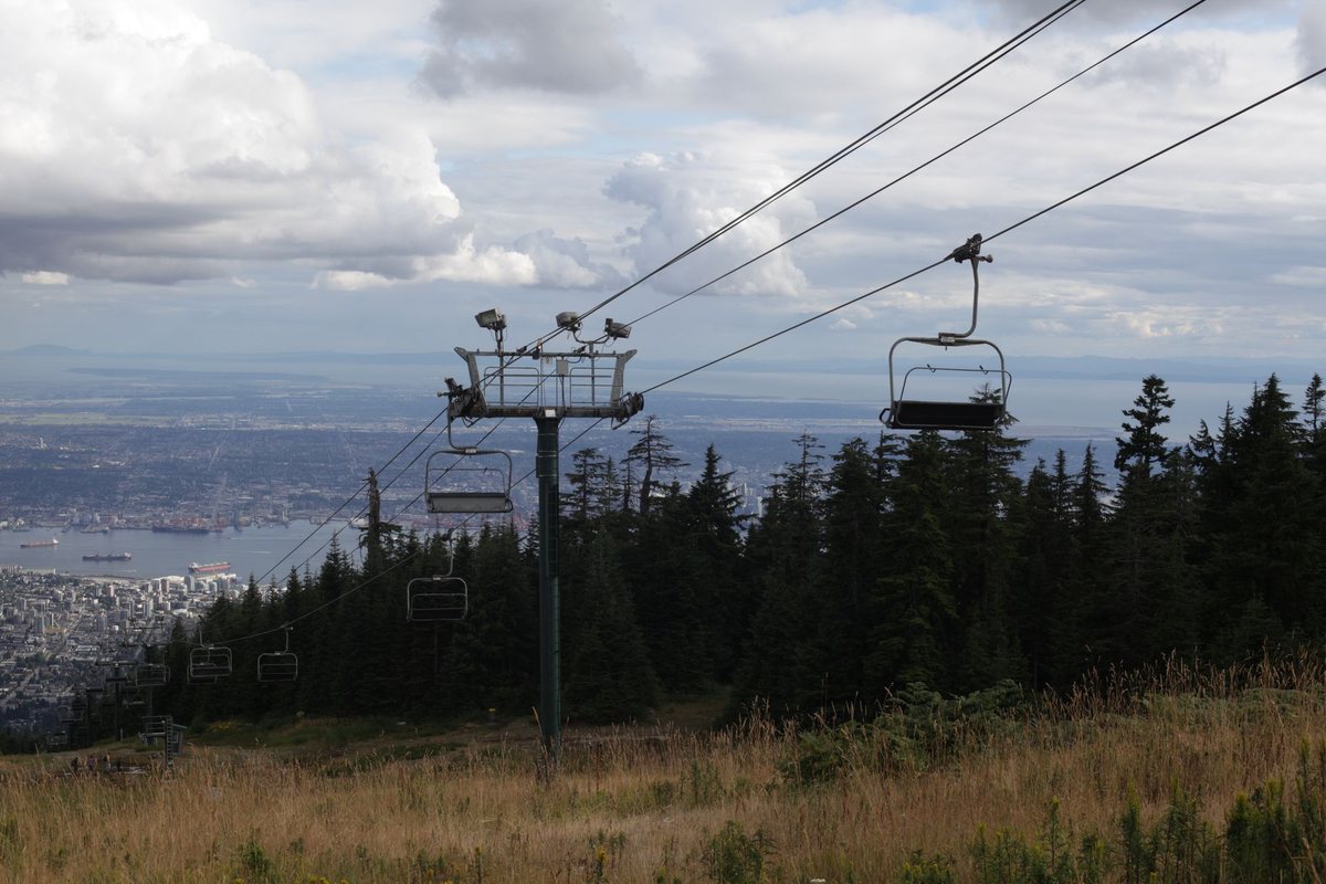 A chairlift on Grouse Mountain in late summer, with the city and harbour below
