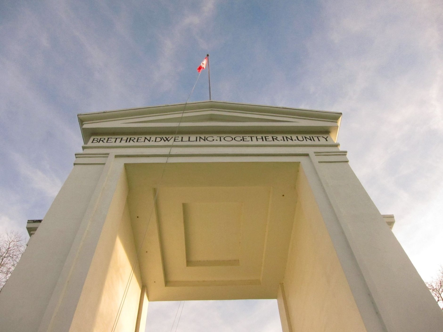 Blick hinauf zum weißen Peace Arch mit seiner gemeißelten Inschrift und einer kanadischen Flagge obenauf