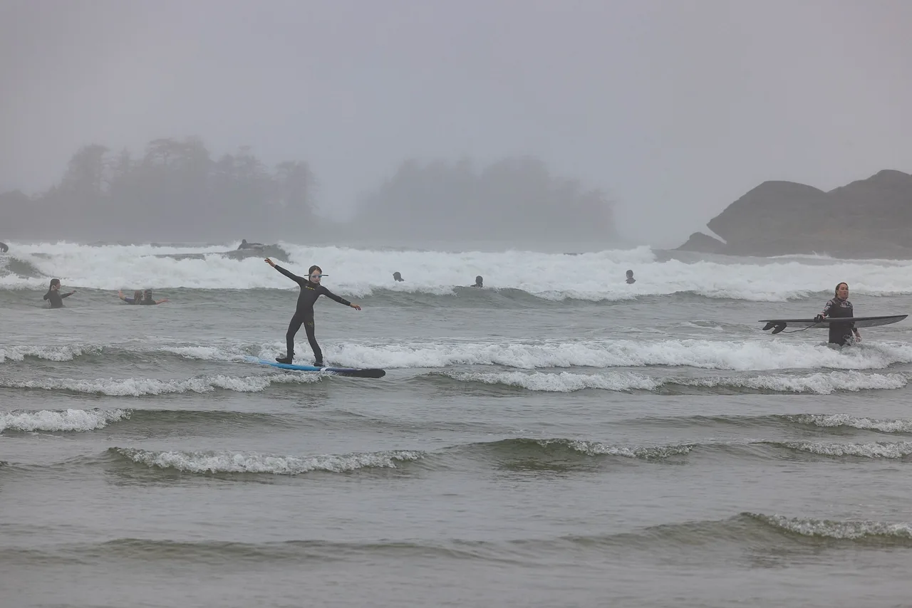 Surfers walking into the waves at Tofino, Vancouver Island