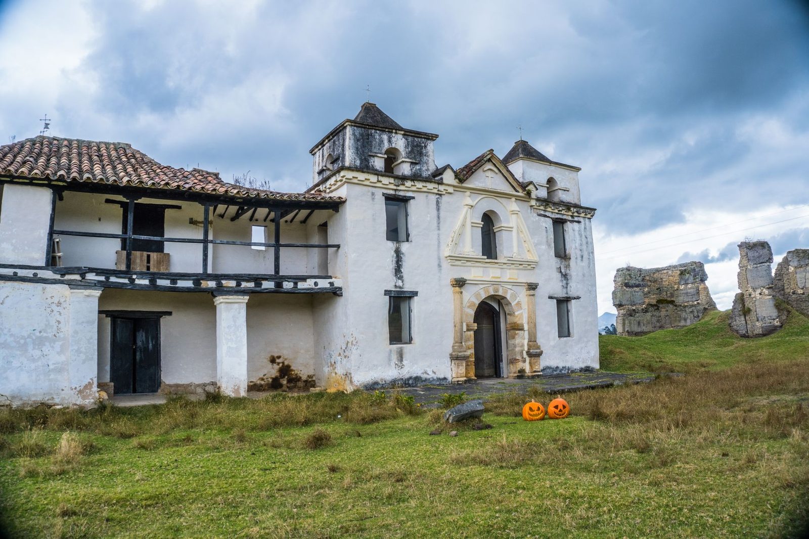 An eerie abandoned house decorated with Halloween pumpkins at dusk