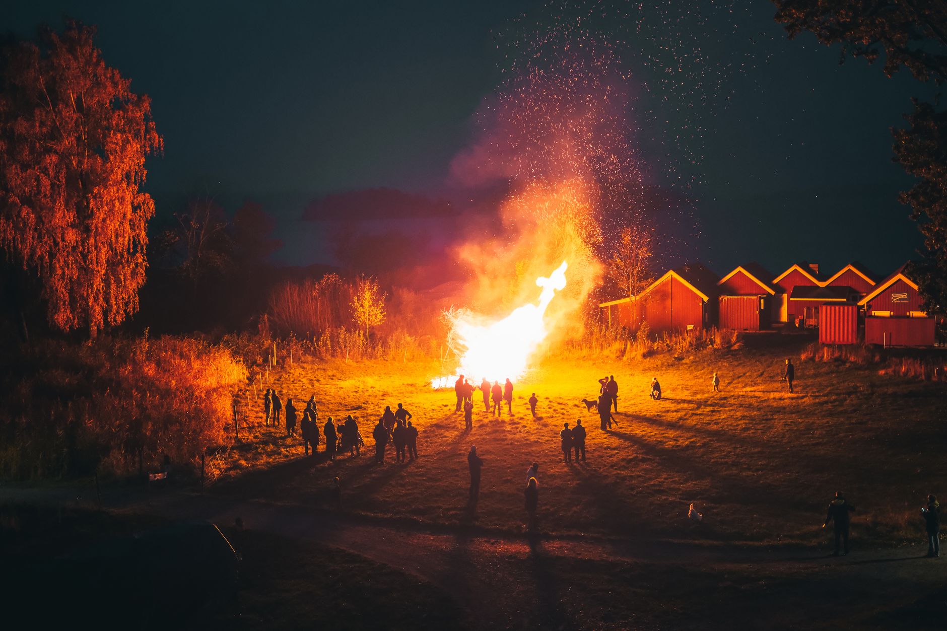 A large communal bonfire burning at night in a rural village