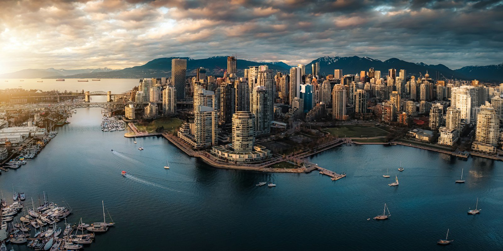 Aerial view of downtown Vancouver towers and marinas, with the North Shore mountains behind