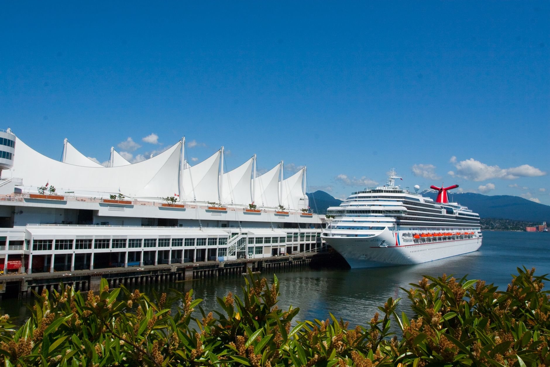 The white sails of Canada Place with a cruise ship docked alongside under a blue sky