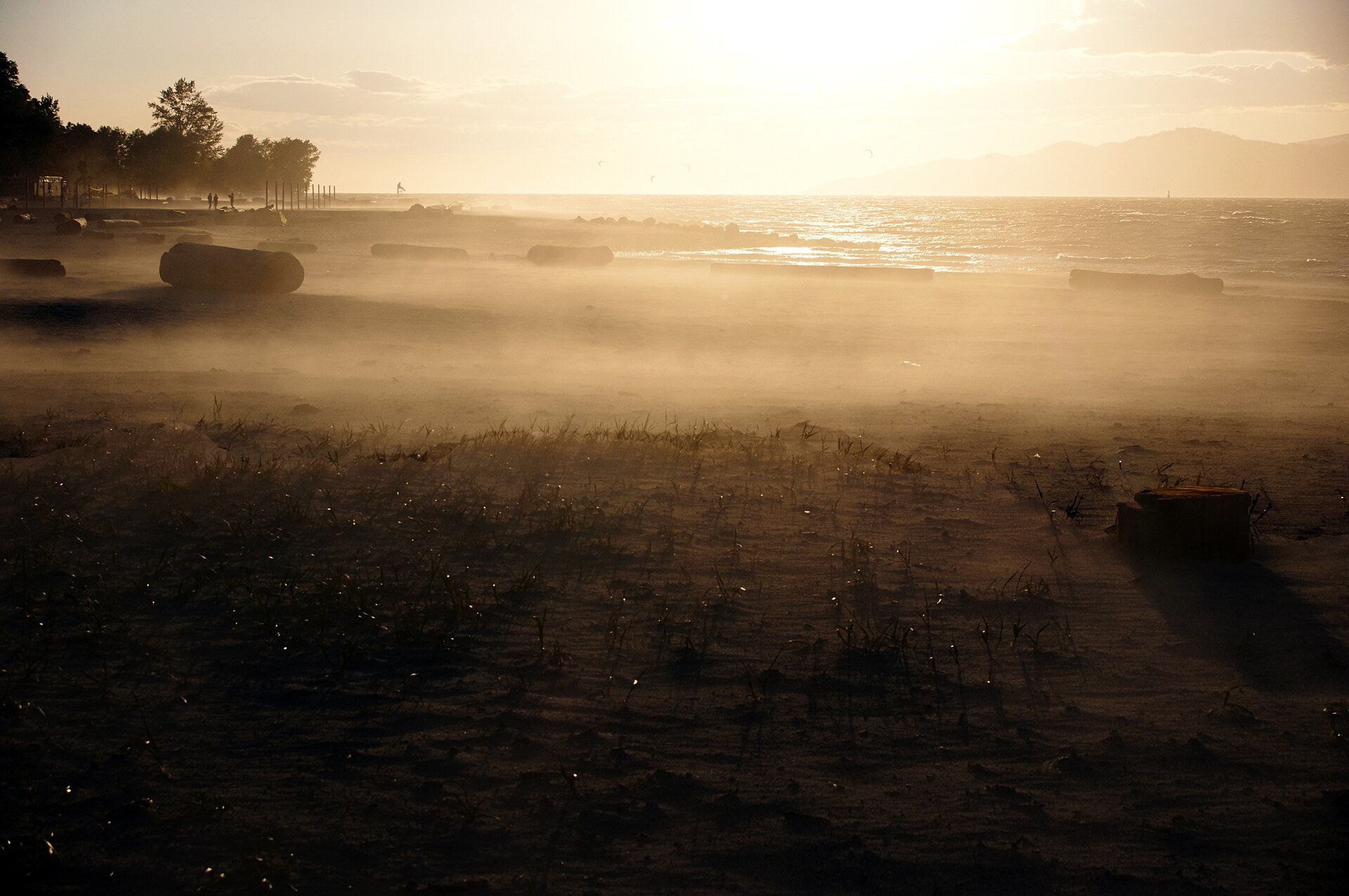Hazy sunset over the sand flats and driftwood logs at Spanish Banks