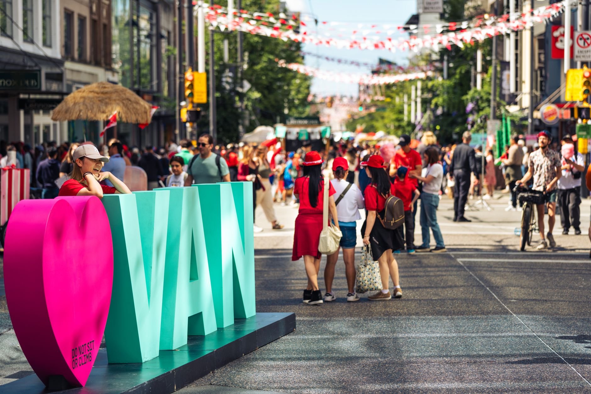 Crowds on a car-free street hung with bunting, beside a giant VAN sign