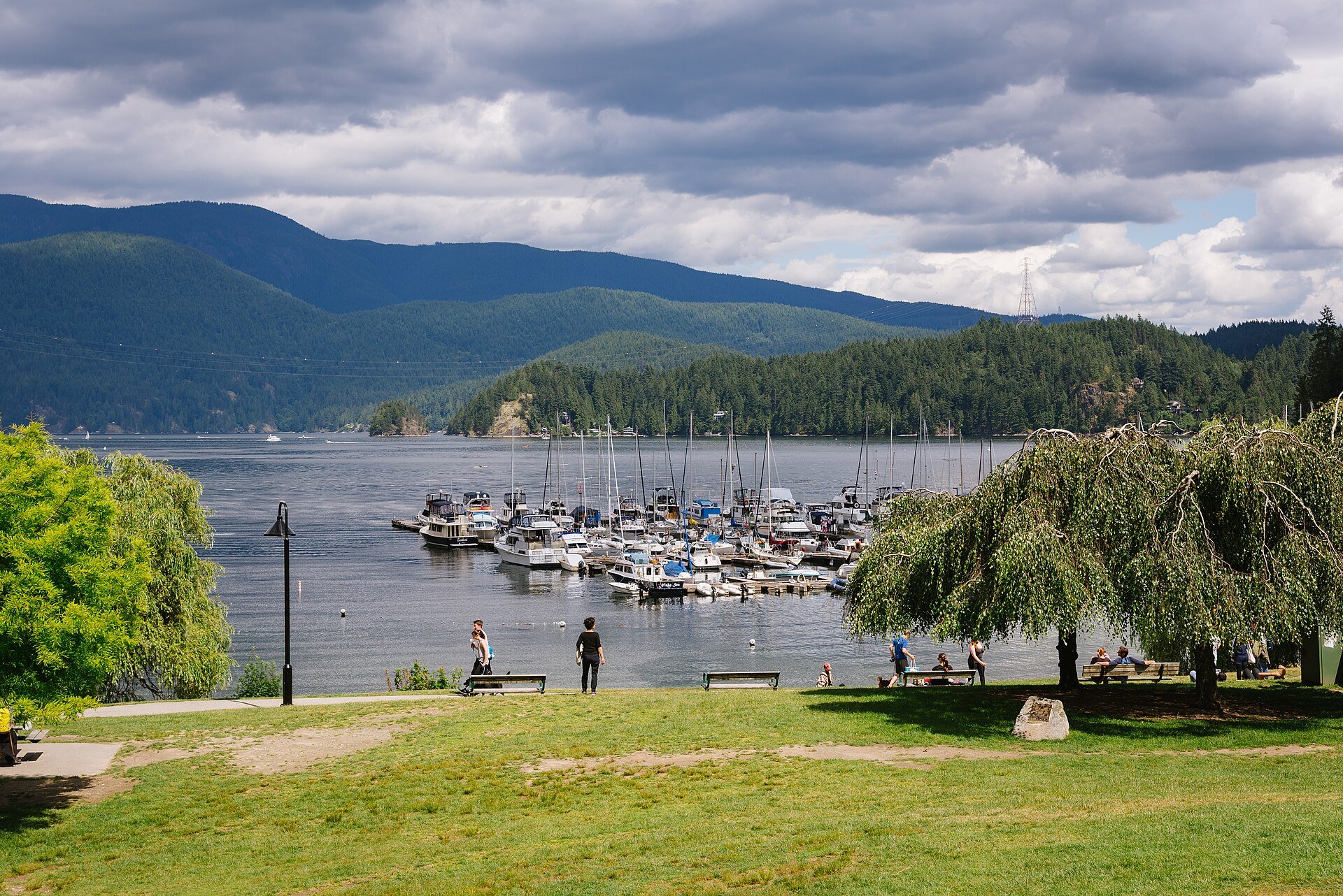 Boats moored in Deep Cove below forested hills, seen from the waterfront park