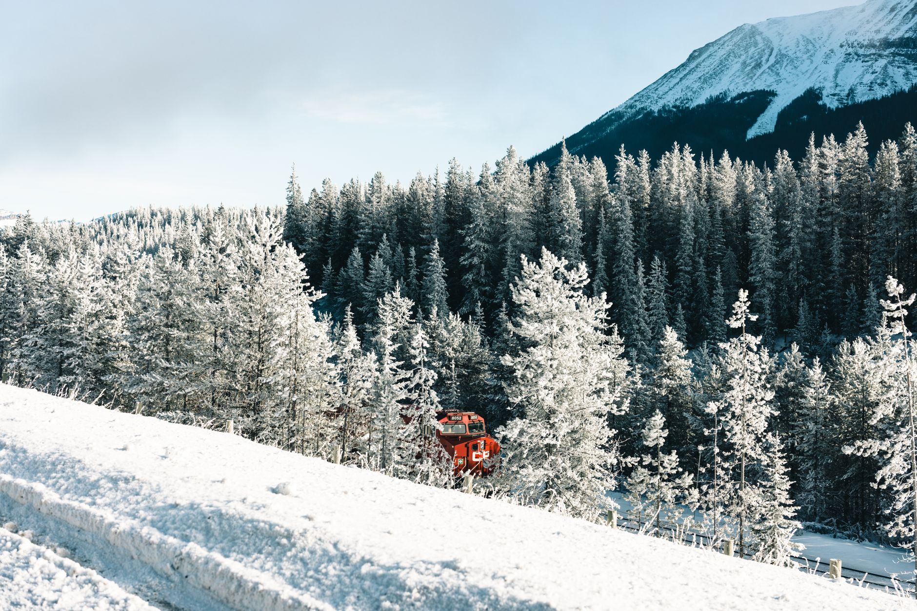 A red train winding through the snow-dusted Canadian Rockies